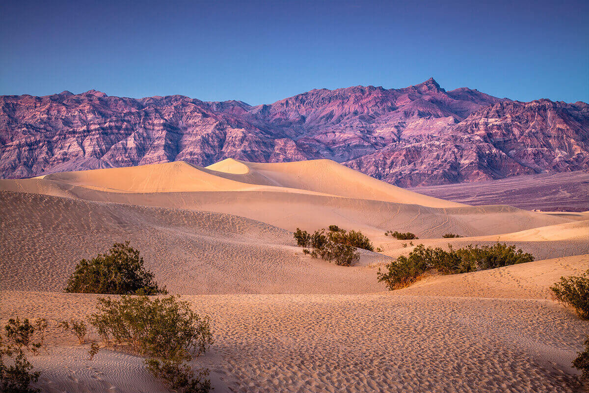 Sand dunes, rainbow-colored rock, mountain peaks in Death Valley, California
