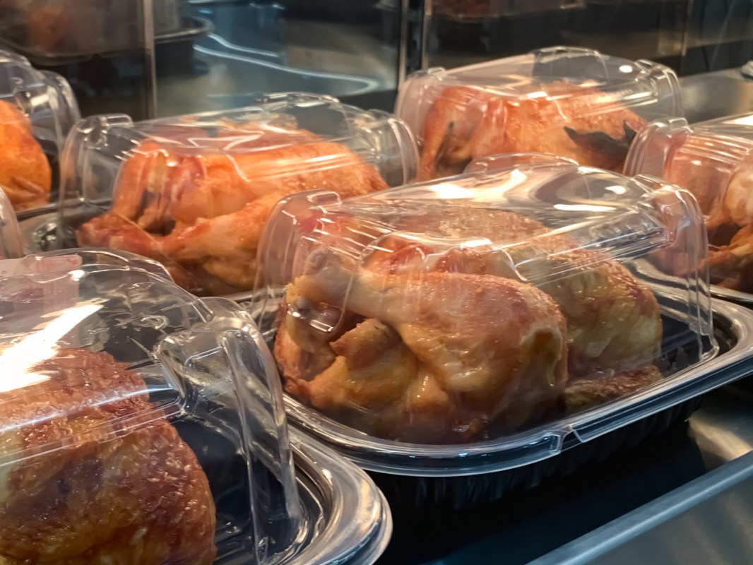 Rotisserie chickens boxed and on display on a store heating shelf