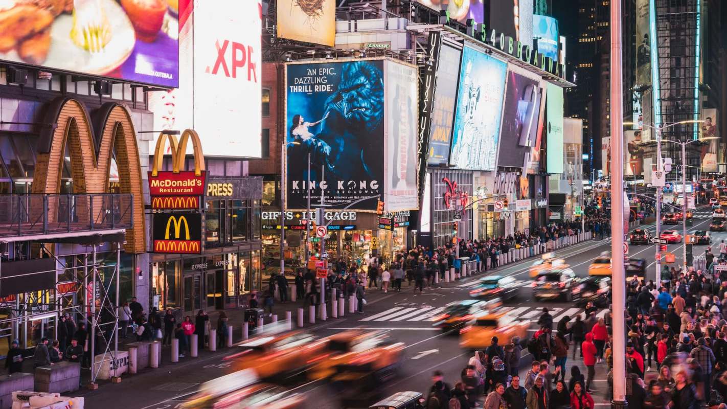 A bustling Times Square at night, featuring bright advertisements and crowds in motion.