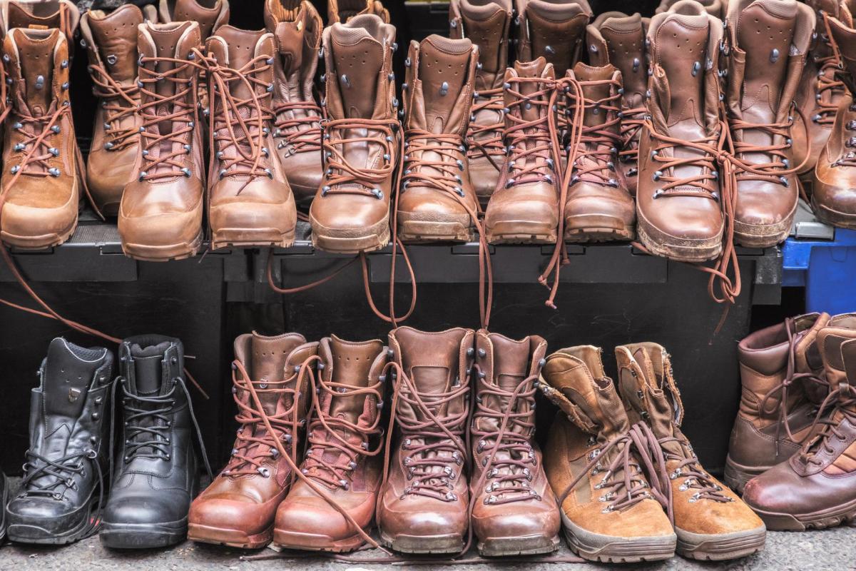 A variety of hiking boots in different shades of brown and black displayed on a shoe rack.
