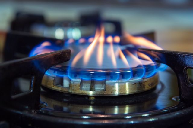 Flames flicker on a gas stove burner in a kitchen.