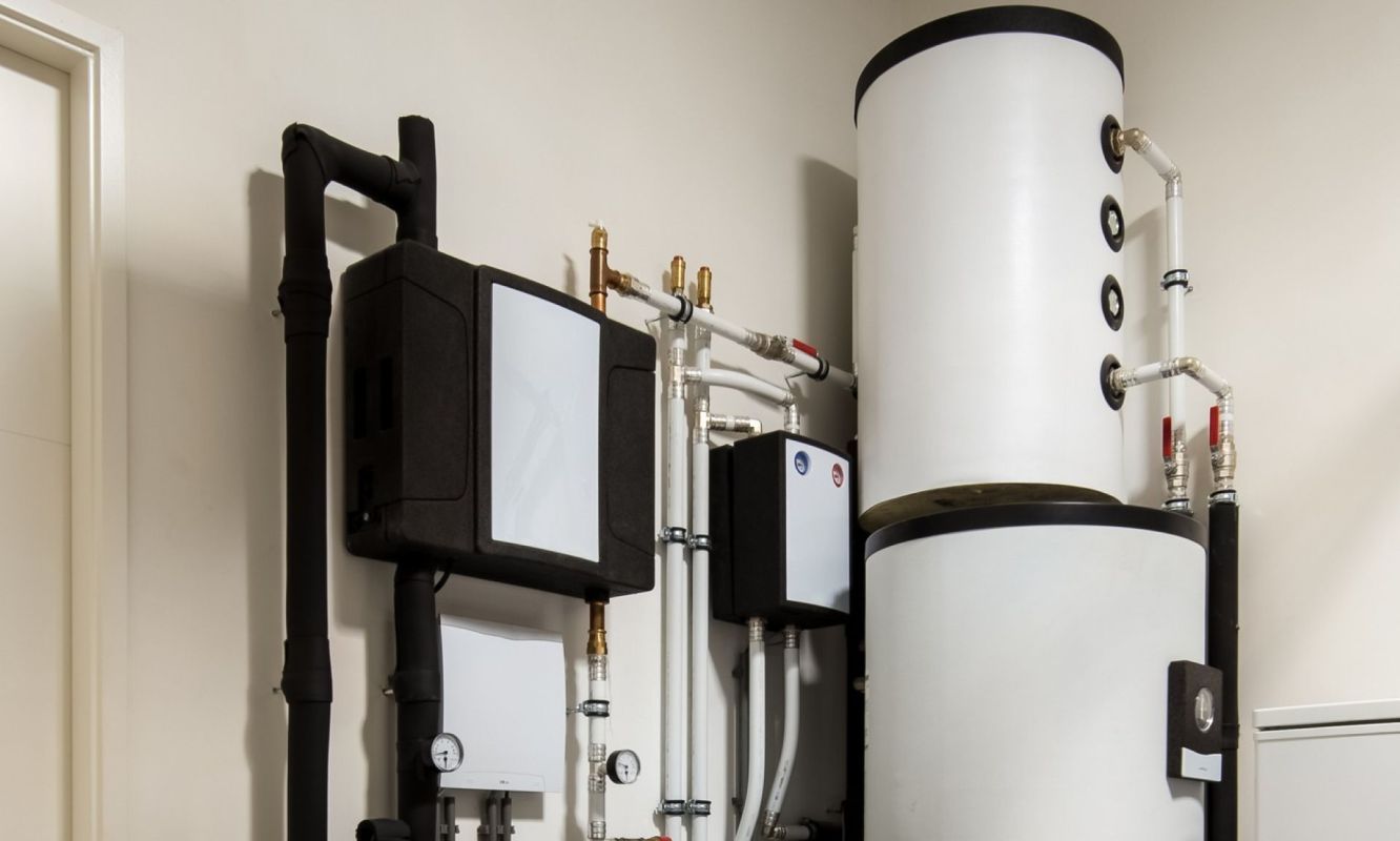 A collection of plumbing equipment including water tanks and pipes mounted on a wall.