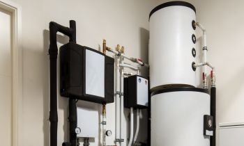 A collection of plumbing equipment including water tanks and pipes mounted on a wall.