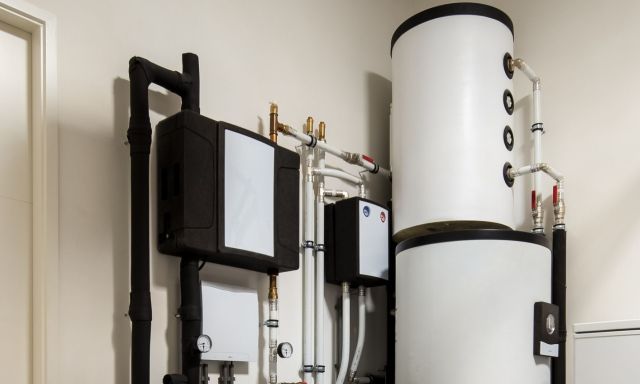 A collection of plumbing equipment including water tanks and pipes mounted on a wall.