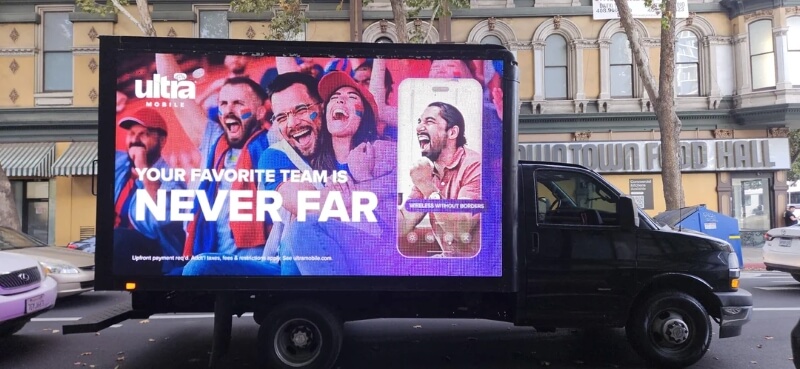 A black van with a mobile billboard advertising Ultra Mobile.