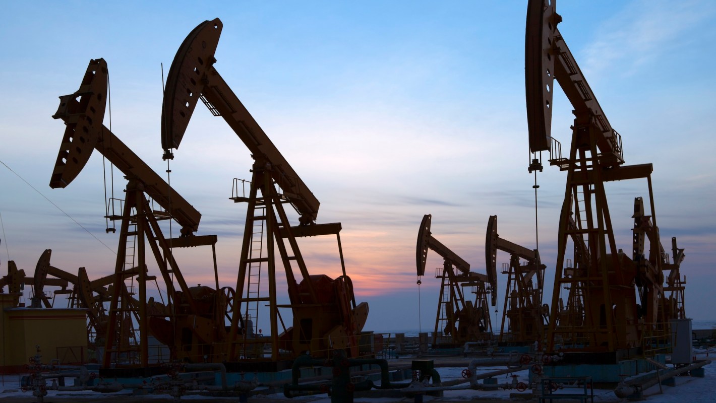 Silhouettes of oil pumps against a colorful sunset sky on an oil field.