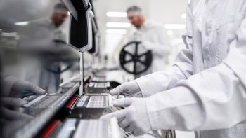 A technician in protective gear working on electric vehicle batteries.
