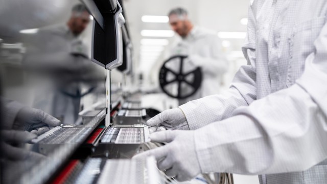 A technician in protective gear working on electric vehicle batteries.