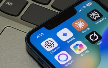 A close-up view of a smartphone screen displaying various AI app icons on a laptop keyboard.