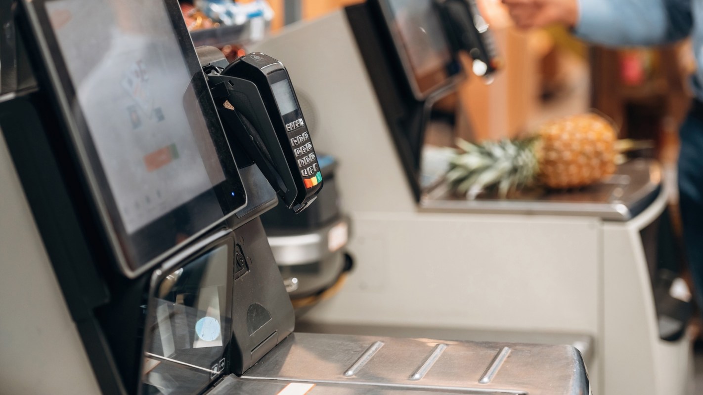 A self-checkout station with a pineapple in the background.