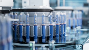 A close-up view of a laboratory machine with blue syringes arranged in a circular configuration.