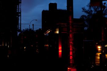 A dimly lit urban street scene at dusk, featuring a bus stop and glowing vehicle lights.