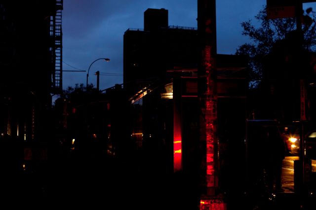 A dimly lit urban street scene at dusk, featuring a bus stop and glowing vehicle lights.