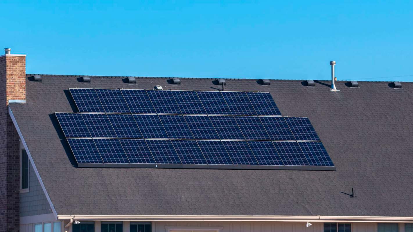 A roof with several solar panels installed, against a clear blue sky.
