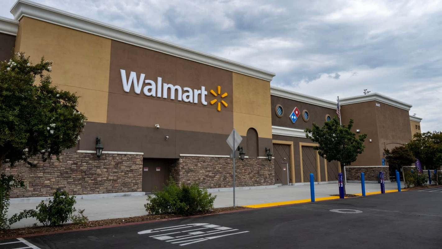 A Walmart store exterior with signage, brown walls, and a nearby Domino's Pizza logo.