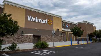 A Walmart store exterior with signage, brown walls, and a nearby Domino's Pizza logo.