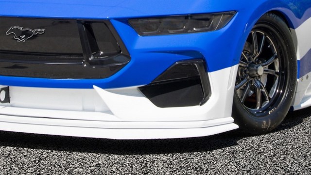 The bottom of an electric Ford Mustang, with the horse emblem on the car's grille.