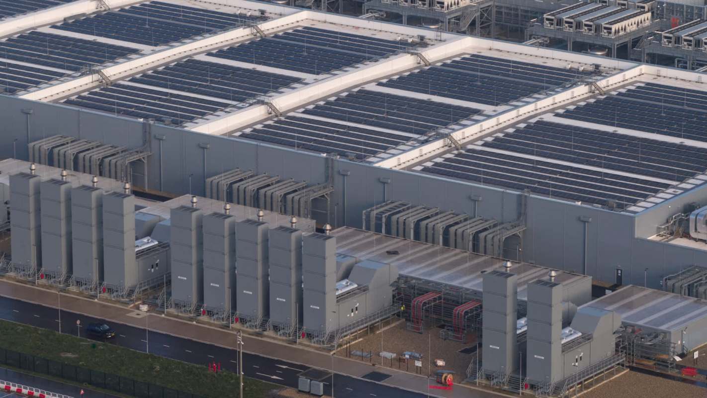 An industrial building of a data center featuring solar panels on the roof and large machinery units on the ground.