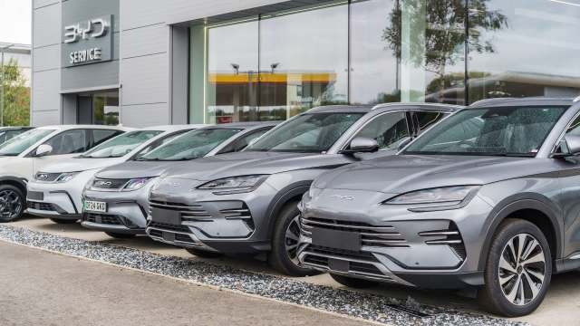 A row of BYD vehicles parked outside a dealership.