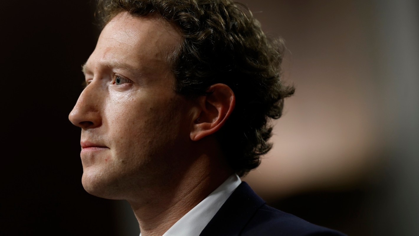 A close-up profile of Mark Zuckerberg with curly hair, looking serious during a formal setting.