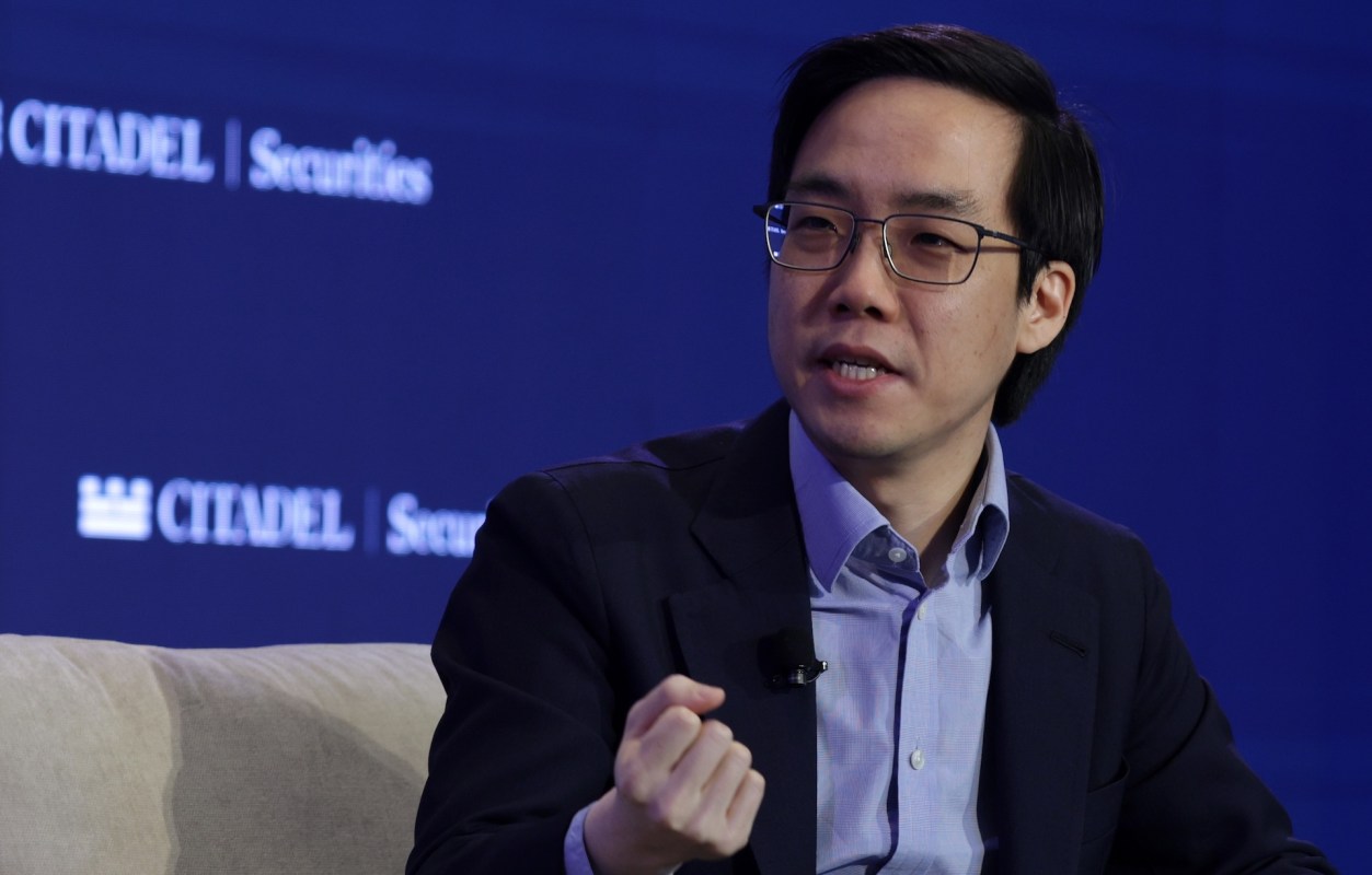 Andy Yen with glasses and in a blazer gestures while speaking during a panel discussion at an event.