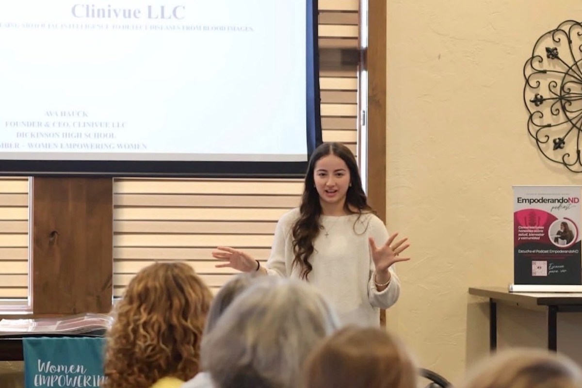 A young woman speaks passionately to an audience during a community empowerment event.