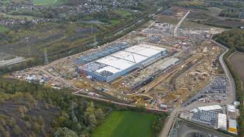 Aerial view of a large construction site with a new data center under development and surrounding land preparation.