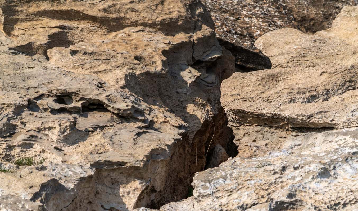 A close-up view of textured, weathered rocks with crevices and patches of grass.