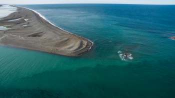 Aerial view of a sandy peninsula extending into a turquoise ocean.