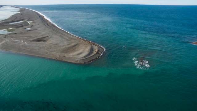 Aerial view of a sandy peninsula extending into a turquoise ocean.