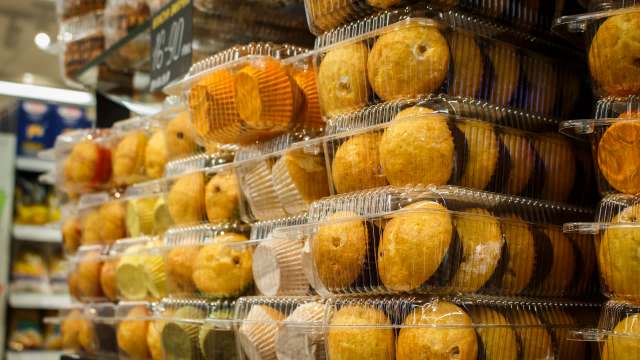 Stacks of transparent containers filled with various baked goods, including muffins and cupcakes, in a store display.