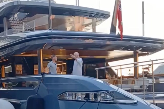 Two men talk on a yacht's deck.