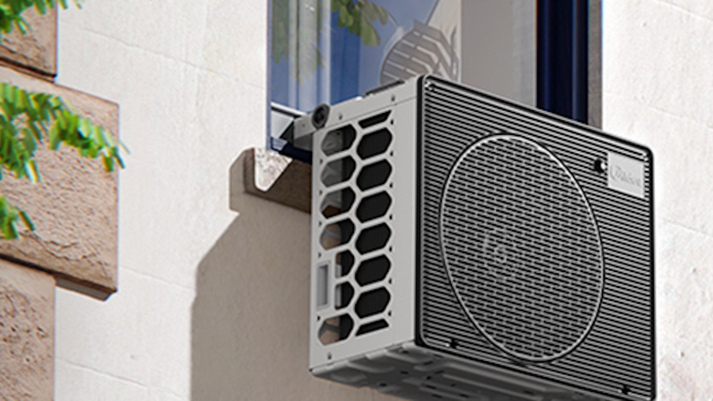 An exterior air conditioning unit is mounted in a window with a light-colored wall in the background.