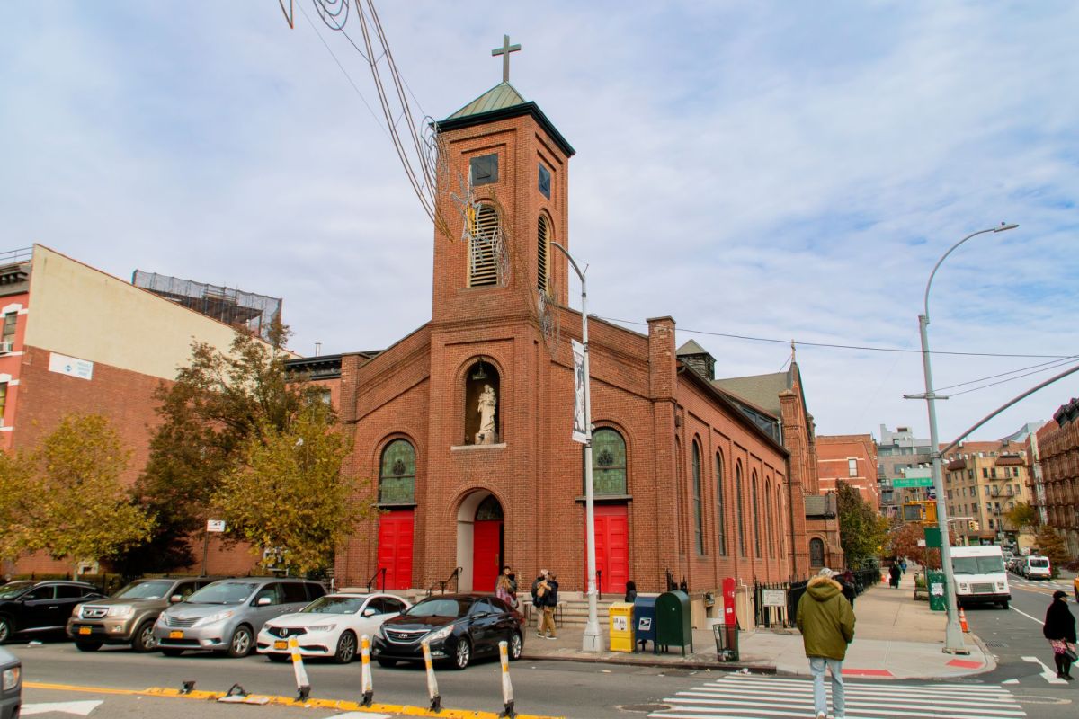 A church in New York City with cars parked in front of it.
