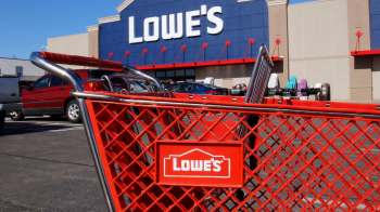 A red shopping cart in front of a Lowe's store with a blue and gray exterior on a sunny day.