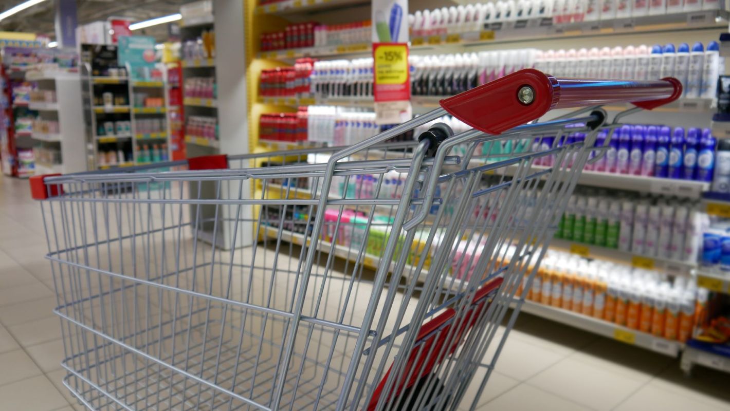 A shopping cart is in an aisle with personal care products.