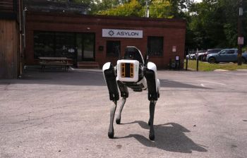 A robotic DroneDog in front of a brick building.