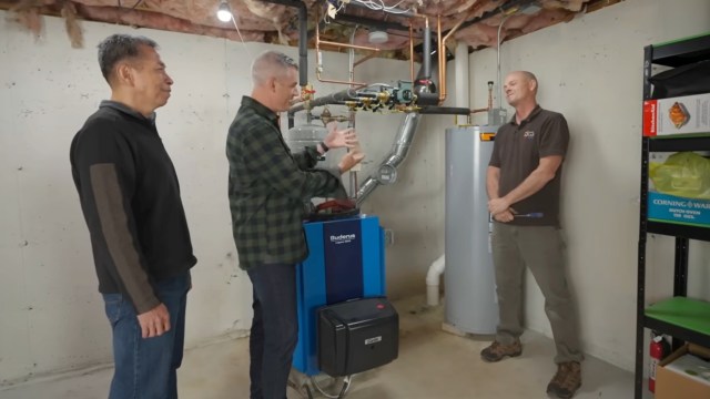 Three people talk about a water heater in a basement.