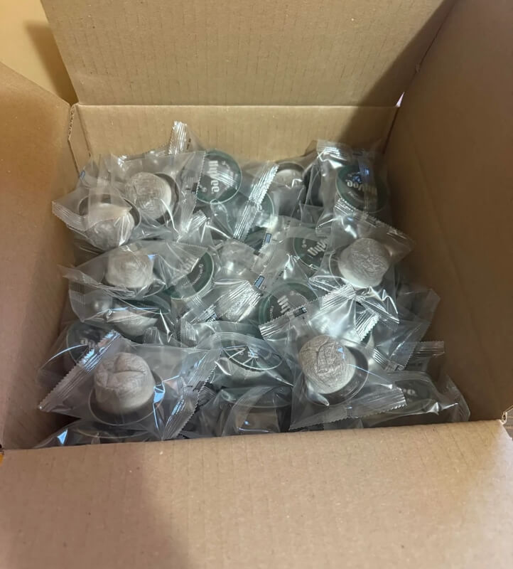 Dozens of K-Cups in a cardboard box, individually wrapped in plastic. 