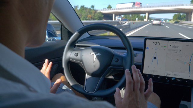 A driver tests a Tesla's autopilot feature on a highway.