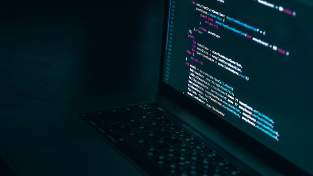 A laptop with programming code on its screen.