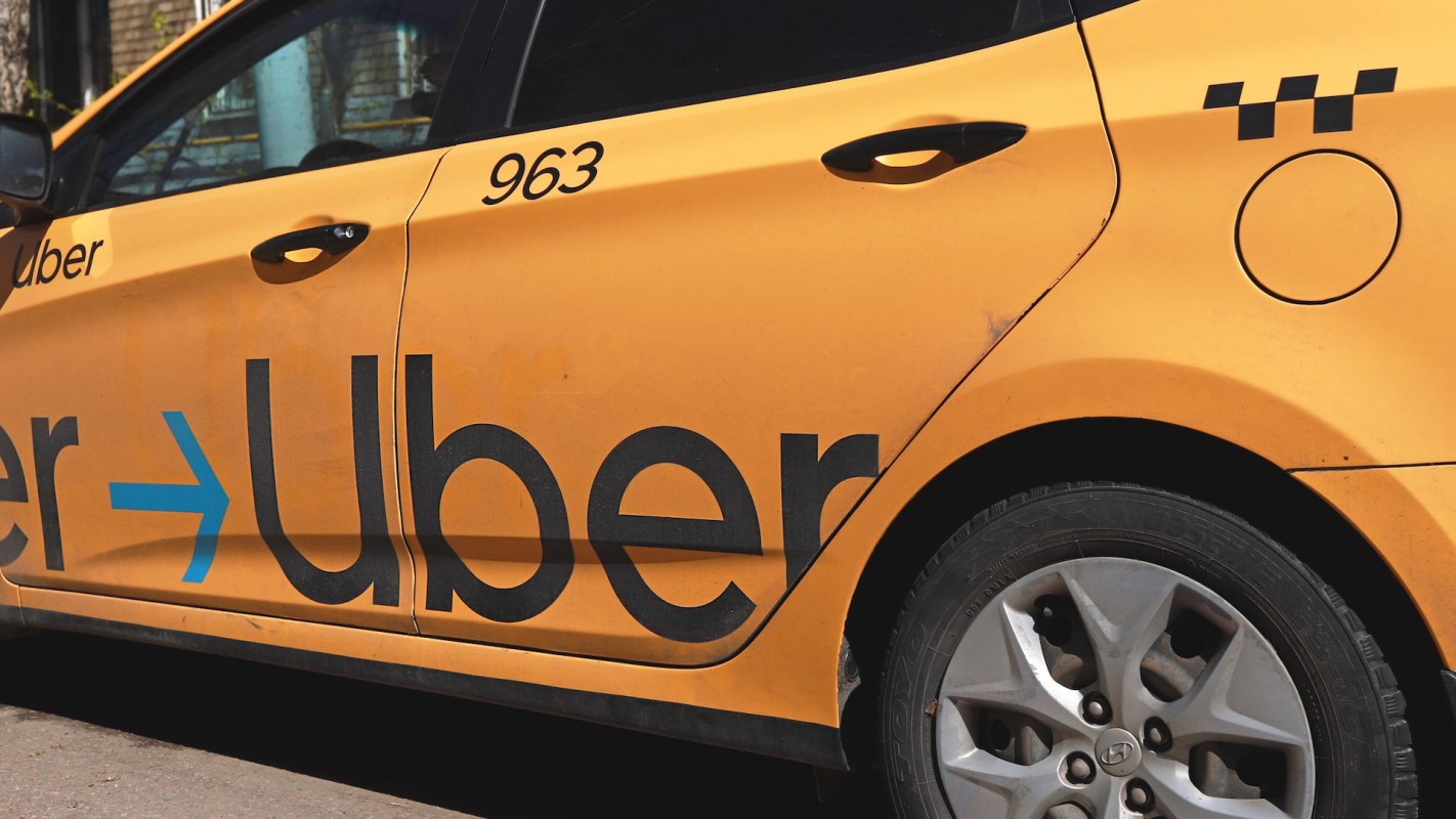 A close-up of an orange Uber car showcasing the logo and number on its side.