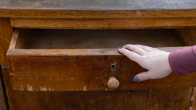 A woman's hand opens a drawer of an old chest