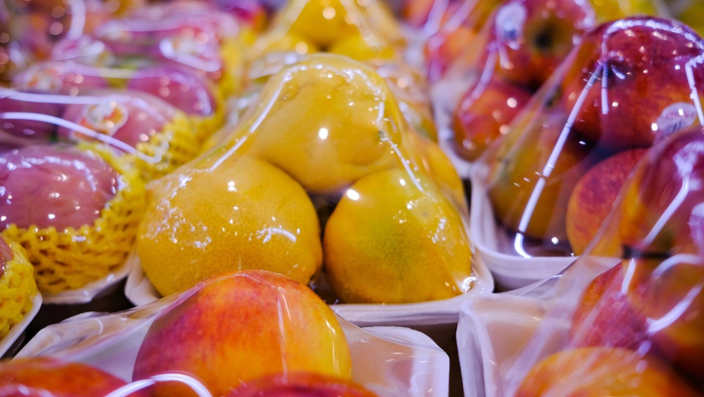 Close-up of various fruits, including pears and apples, packaged in clear plastic wrapping.