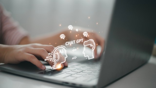 A person typing on a laptop with digital icons representing AI and chat interactions floating above.
