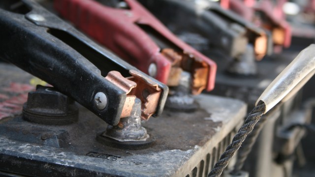 Close-up of battery terminals with red and black jumper cables connected.