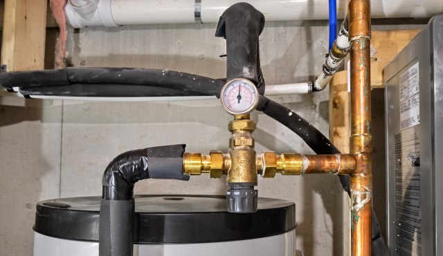 Plumbing equipment with a pressure gauge and various pipes in a basement.
