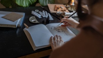 A person hand inking a cartoon in a sketchbook.
