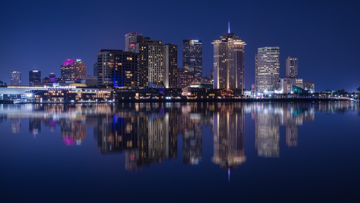 A nighttime New Orleans skyline reflecting in water.