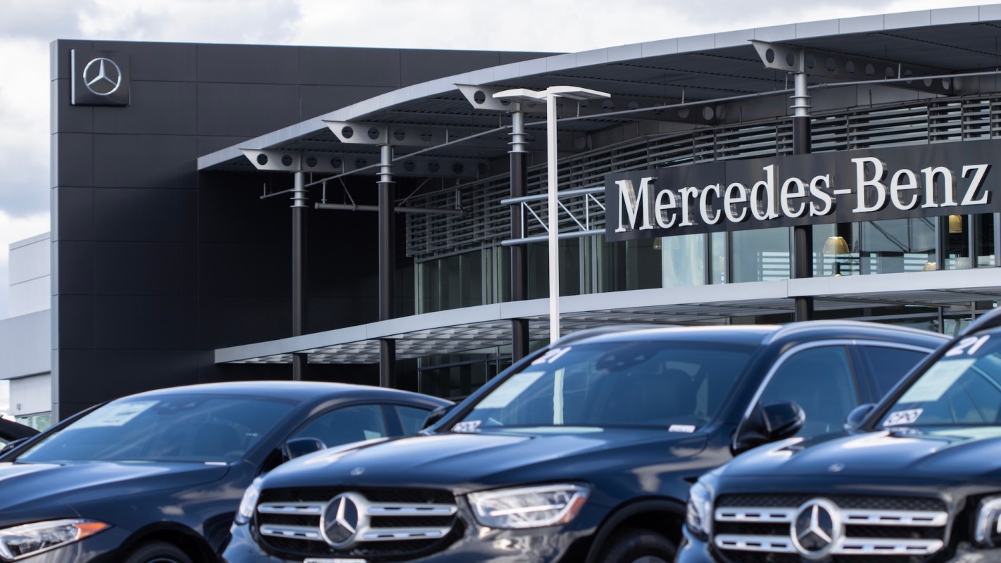 A Mercedes-Benz dealership featuring several parked black cars in front of a modern building.